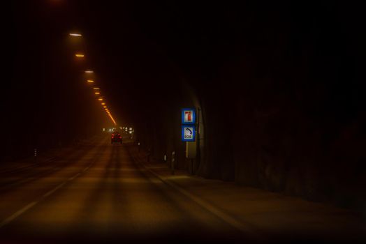 Dark underground tunnel long paved road with dim warm lighting and SOS signage