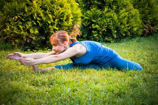 Beautiful young woman doing yoga exercises outdoors