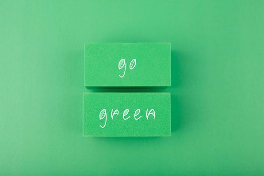 Modern minimal flat lay with go green inscription against light pastel green background. Concept of go green, recycle, reduce, reuse and eco friendly lifestyle