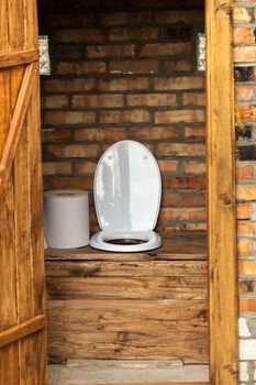 A simple village toilet with a huge roll of toilet paper.Large roll of toilet paper in the toilet.