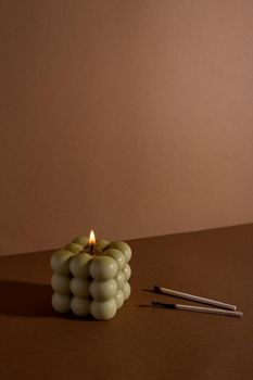 Aromatic scented soy candle with smoke on beige brown textile background , modern bubble candle still life side view