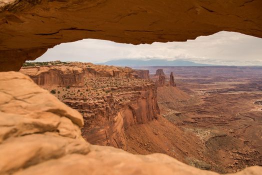 Looking through the window that is Mesa Arch at Canyonlands National Park Utah out into the vast red rock canyon layers.