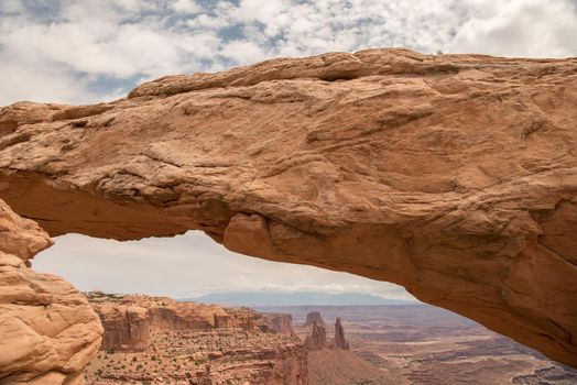 A close up of Mesa Arch at Canyonlands National Park with layers of clouds in the background.
