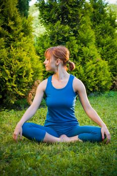 Beautiful young woman doing yoga exercises outdoors