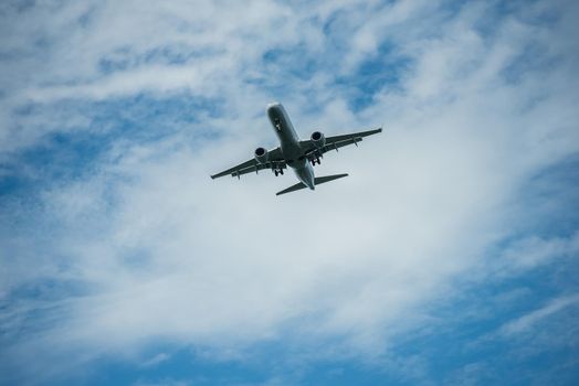 Airplane close up flying through blue sky with puffy clouds.