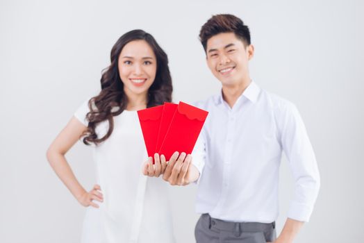 Vietnamese couple exchanging red lucky money envelopes. Tet holiday.