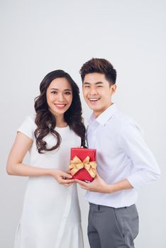 Love. Handsome young Vietnamese man giving present to beautiful woman at home
