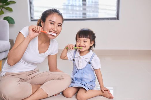 Mother and daughter brushing their teeth