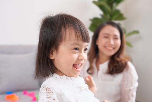 Little girl and her mom drinking milk sitting on sofa at home. Motherhood and care, healthy eating and lifestyle, early development concept, copy space