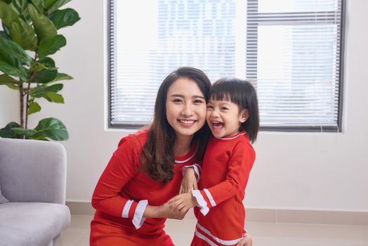 Happy young mother laughing with her little daughter in the morning. Having fun together. Joyful family time at home. 