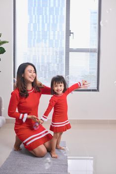 Happy young mother laughing with her little daughter in the morning. Having fun together. Joyful family time at home. 