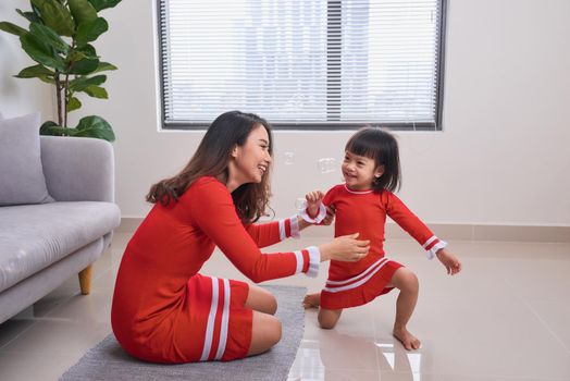 Happy young mother laughing with her little daughter in the morning. Having fun together. Joyful family time at home. 