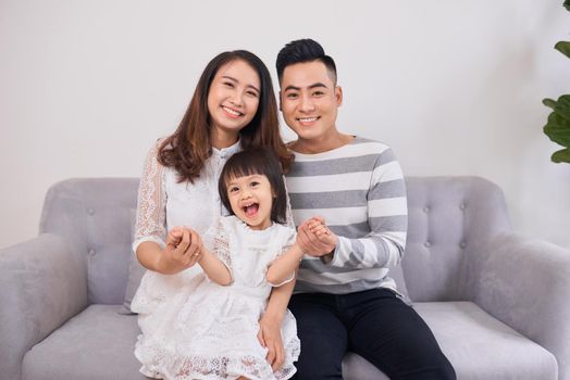 Shot of a laughing little girl sitting in couch with her parents in the morning.