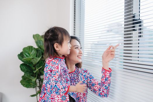 Vietnamese mother and daughter in Ao Dai Traditional dress, celebrate new year at home. Tet Holiday.