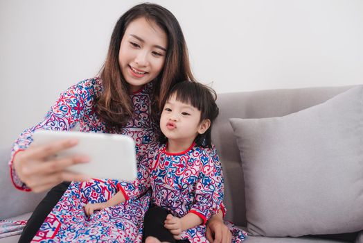 Vietnamese mother and daughter in Ao Dai Traditional dress, taking selfie photo.