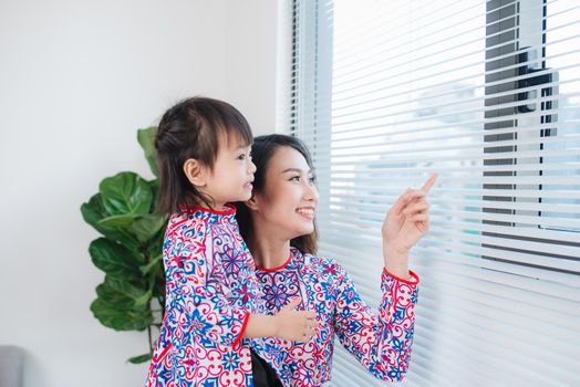 Vietnamese mother and daughter in Ao Dai Traditional dress, celebrate new year at home. Tet Holiday.