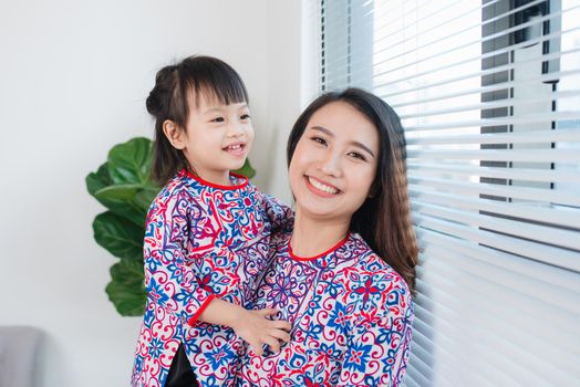 Vietnamese mother and daughter in Ao Dai Traditional dress, celebrate new year at home. Tet Holiday.