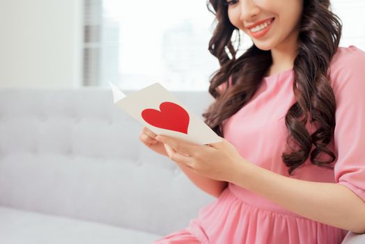 Cute girl reading a love card from her boyfriend