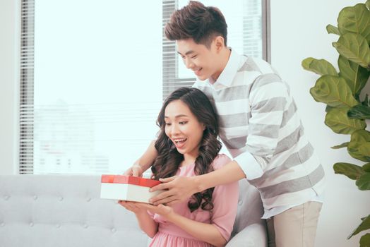 Young couple opening parcel gift box on the couch