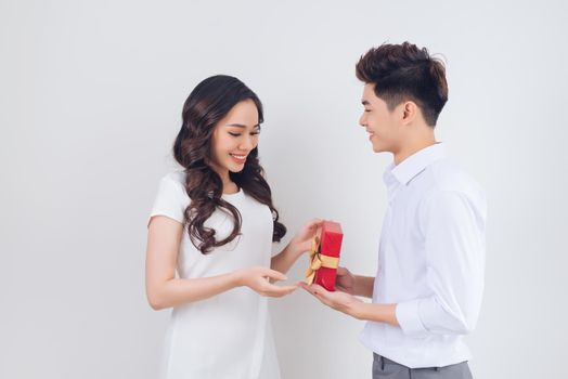 Love. Handsome young Vietnamese man giving present to beautiful woman at home