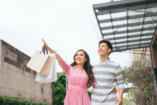 Portrait of happy couple with shopping bags after shopping in city