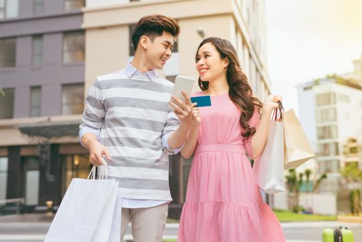 Beautiful asian couple shopping with a credit card in the city