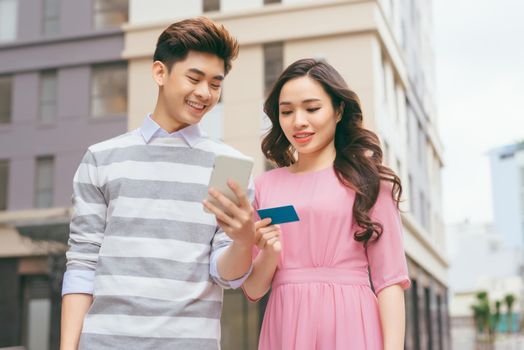 Beautiful asian couple shopping with a credit card in the city