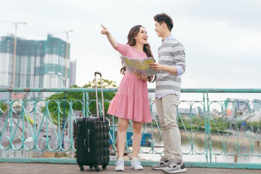 Happy asian couple on vacation sightseeing city with map