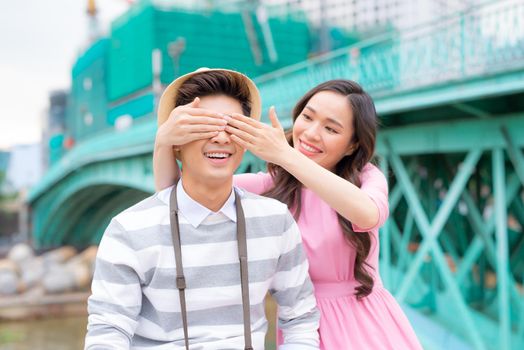 Young man closing his girfriend eyes to make a surprise for her - Love, holiday and people concept