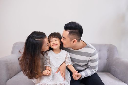 Shot of a laughing little girl sitting in couch with her parents in the morning.