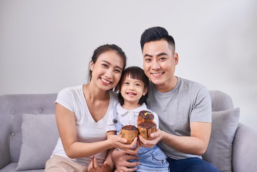 Lively family eating cupcakes in the living room at home