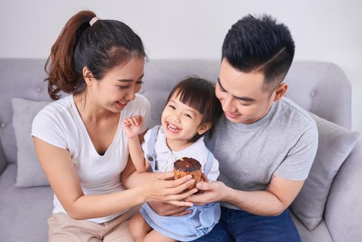 Lively family eating cupcakes in the living room at home