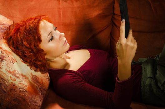 Young woman on a couch interacting with tablet pc or e-reader