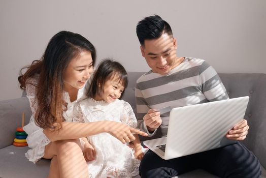 Parents and daughter playing together with a laptop on a couch
