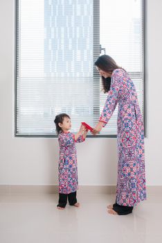 Vietnamese mother and daughter in Ao Dai Traditional dress, celebrate new year at home. Tet Holiday.