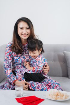 Vietnamese mother and daughter in Ao Dai Traditional dress, celebrate new year at home. Tet Holiday.