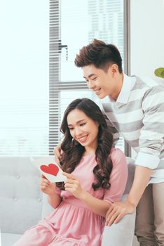 Young love asian couple holding valentine's greeting card