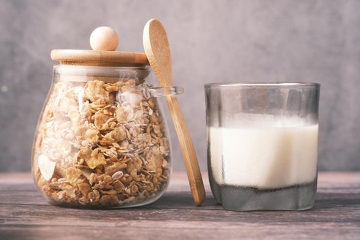 muesli with dried fruit in a jar with glass of milk on table