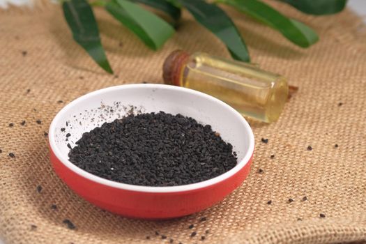 Black Cumin in a container and oil in a bottle on table ,