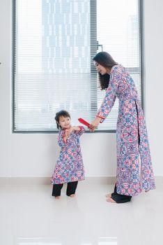 Vietnamese mother and daughter in Ao Dai Traditional dress, celebrate new year at home. Tet Holiday.