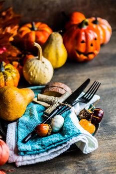 Autumnal table setting with leaves and  pumpkin on wooden table