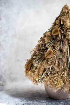 Christmas interior decoration with xmas tree made with dry grass, branches and leaves