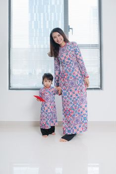 Vietnamese mother and daughter in Ao Dai Traditional dress, celebrate new year at home. Tet Holiday.