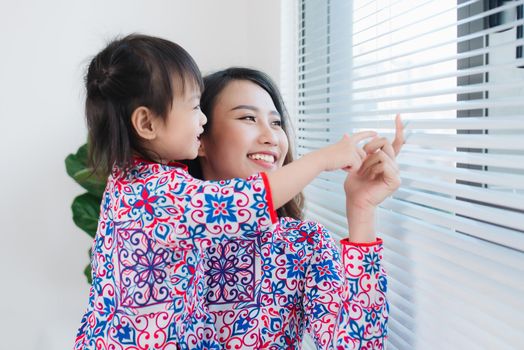 Vietnamese mother and daughter in Ao Dai Traditional dress, celebrate new year at home. Tet Holiday.