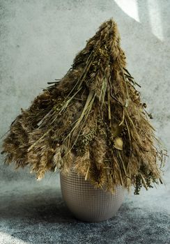 Christmas interior decoration with xmas tree made with dry grass, branches and leaves