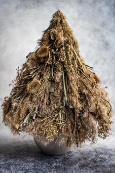 Christmas interior decoration with xmas tree made with dry grass, branches and leaves