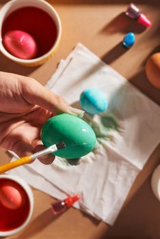 Holidays, tradition and people concept - close up of man hands coloring easter eggs with brush