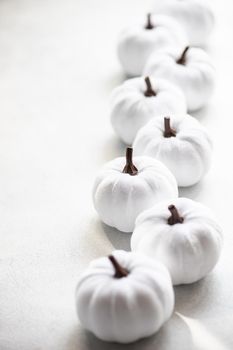 White handmade textile pumpkins as a Thanksgiving card on same color concrete background