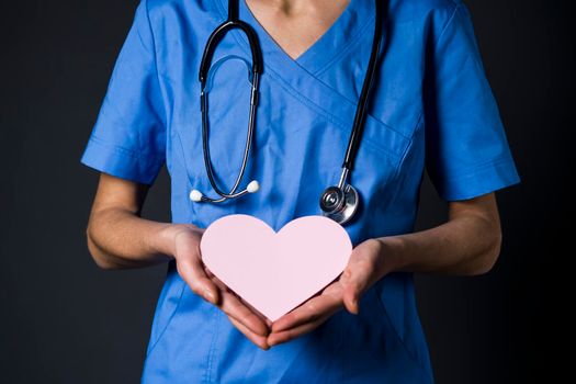Young woman doctor, a cardiologist gently holds a pink heart in her hands. The nurse treats patients with love, restoration of cardiac activity. A new part of life after a toxic relationship.