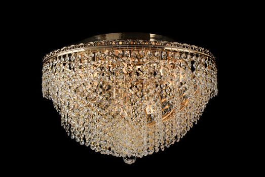 Large golden chandelier isolated over black background